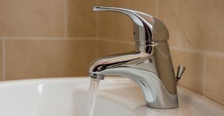 Un lavabo de baño con agua corriendo desde un grifo cromado.