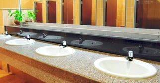Una fila de lavabos en un baño público con un espejo grande.