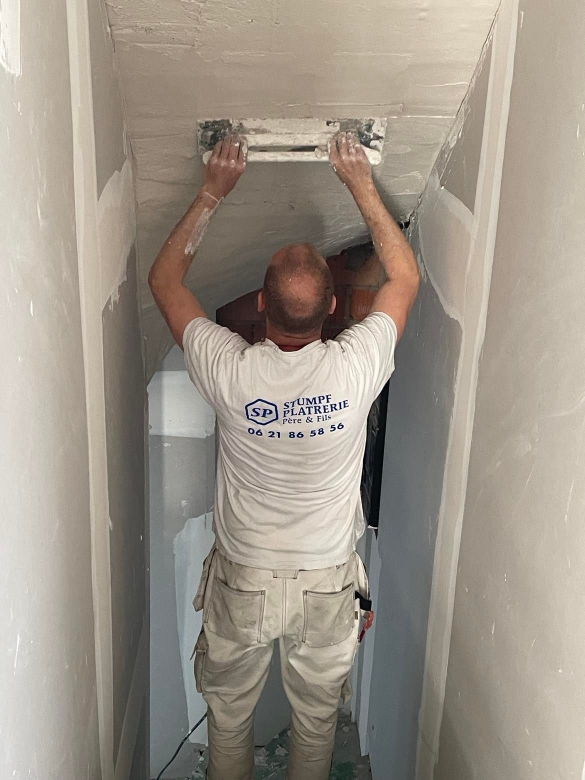 Plaquiste appliquant de l'enduit sur un plafond à  la taloche