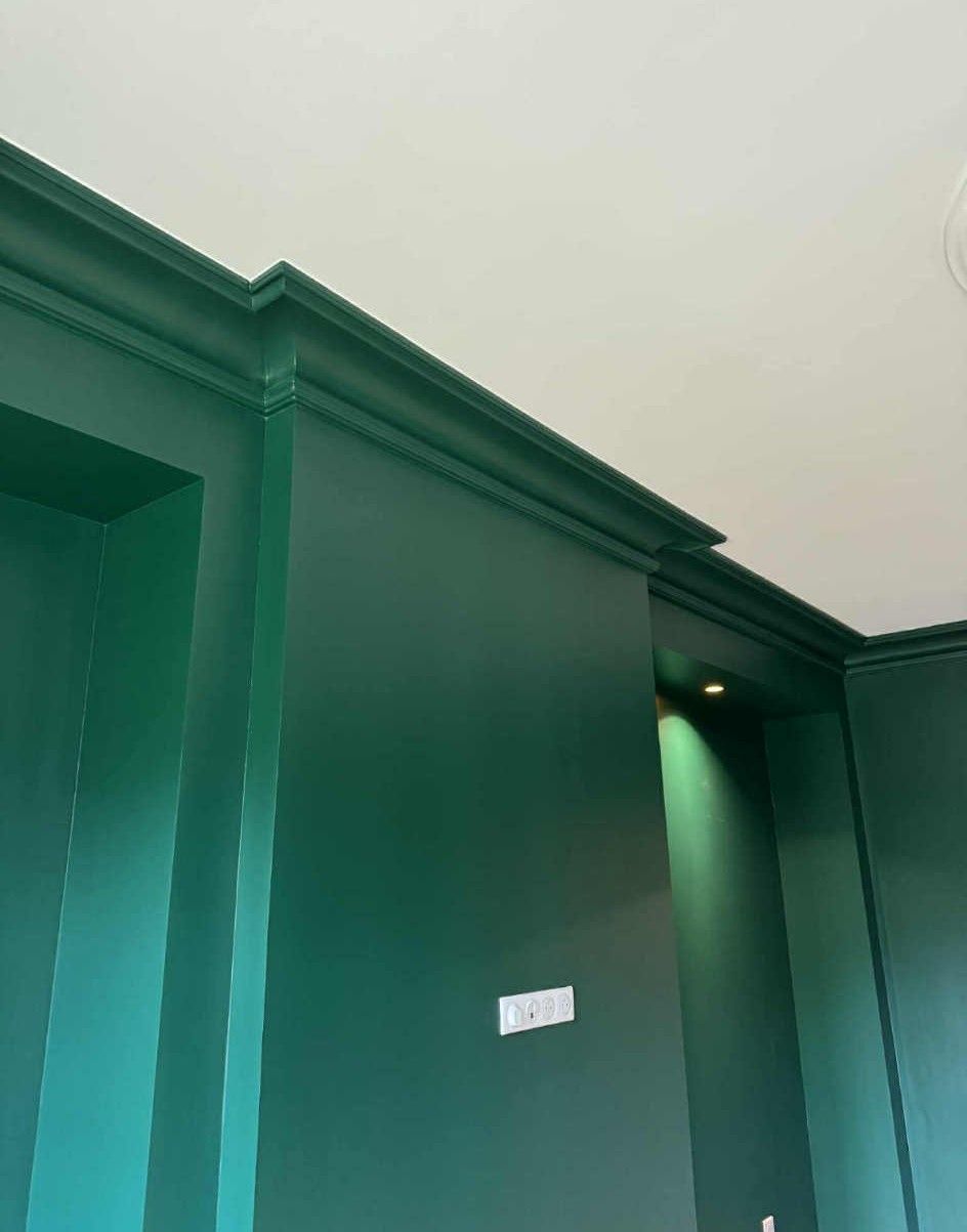 Moulure de colonne sur un mur gris, plinthe blanche et parquet clair