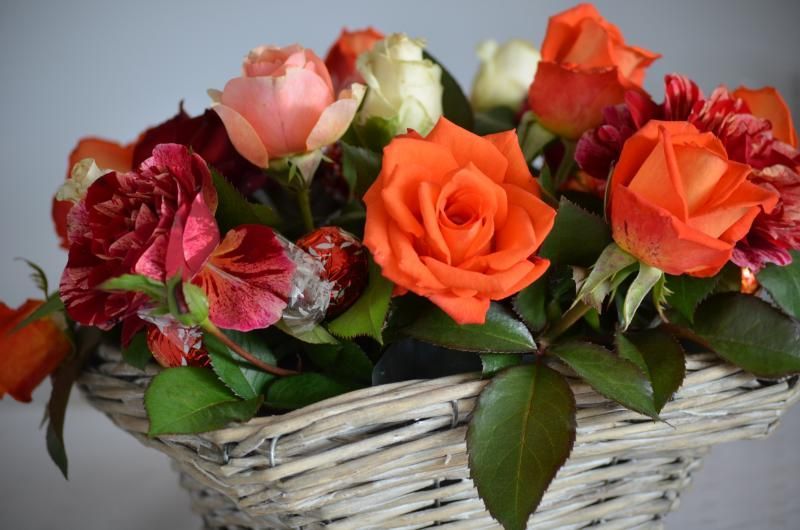 Ein Weidenkorb gefüllt mit orangen und rosa Rosen. Foto vom Gmaandhuus Wilchingen