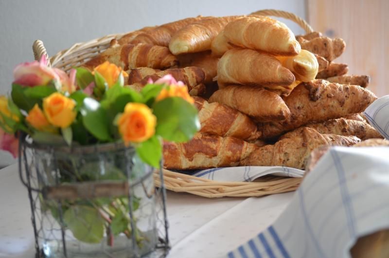 Ein Korb mit Croissants steht auf einem Tisch neben einer Vase mit Blumen. Foto vom Gmaandhuus Wilchingen