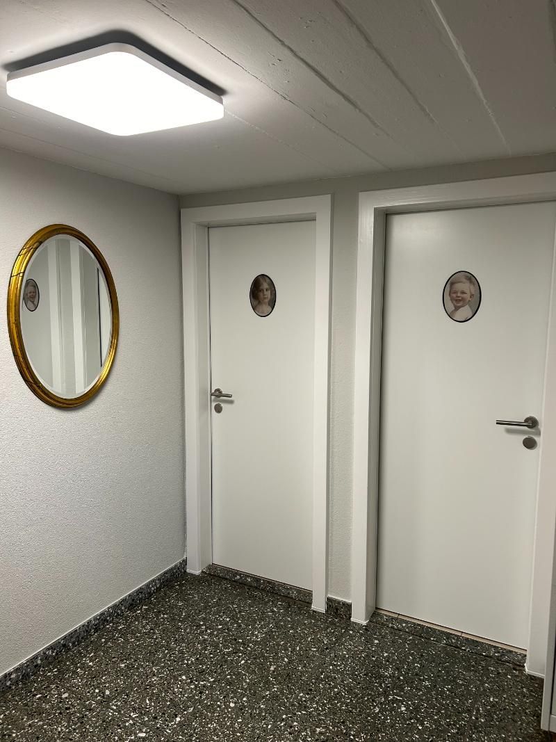 Ein Flur mit zwei weissen WC-Türen und einem Spiegel an der Wand. Foto vom Gmaandhuus Wilchingen