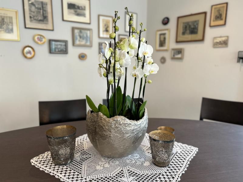 Ein Tisch mit einer Vase mit Blumen und zwei Kerzen darauf. Foto vom Gmaandhuus Wilchingen