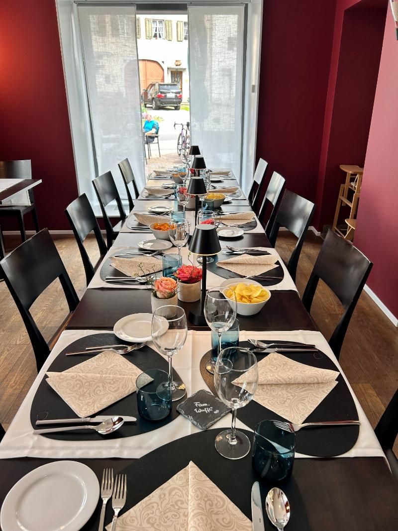 Ein langer Tisch im Restaurant mit Tellern, Besteck und Gläsern darauf. Foto vom Gmaandhuus Wilchingen