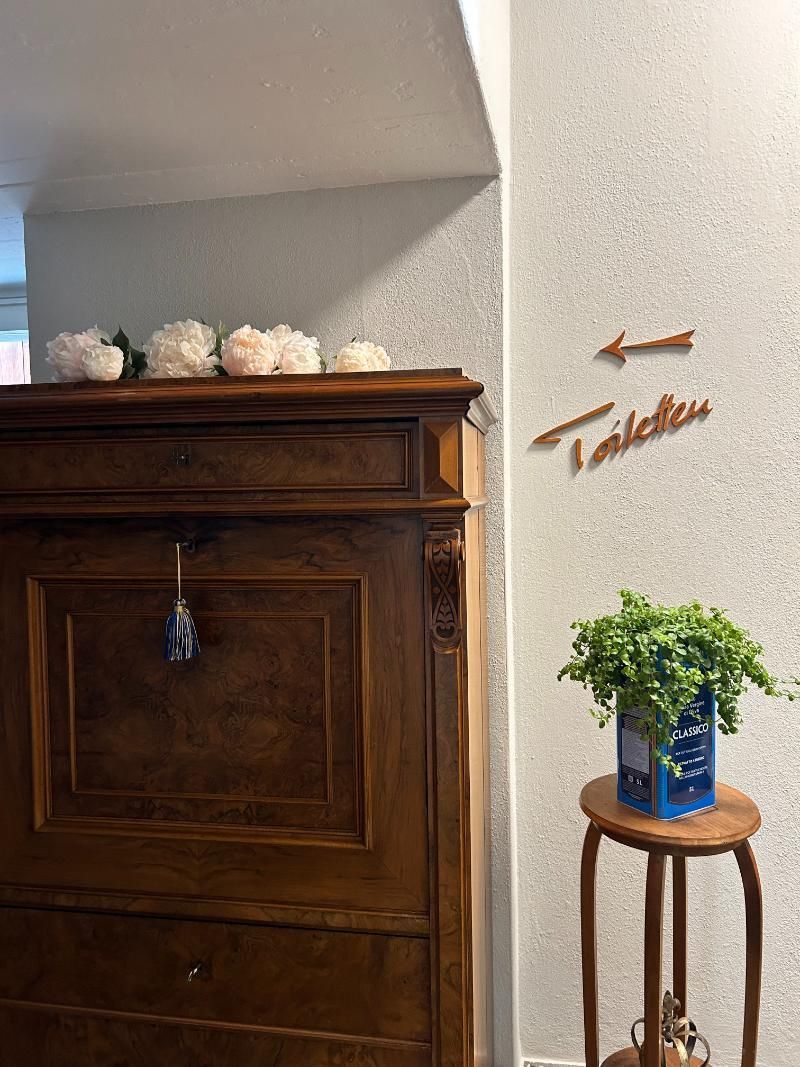 Eine Holzkommode mit einer Pflanze auf einem kleinen Tisch daneben. Foto vom Gmaandhuus Wilchingen