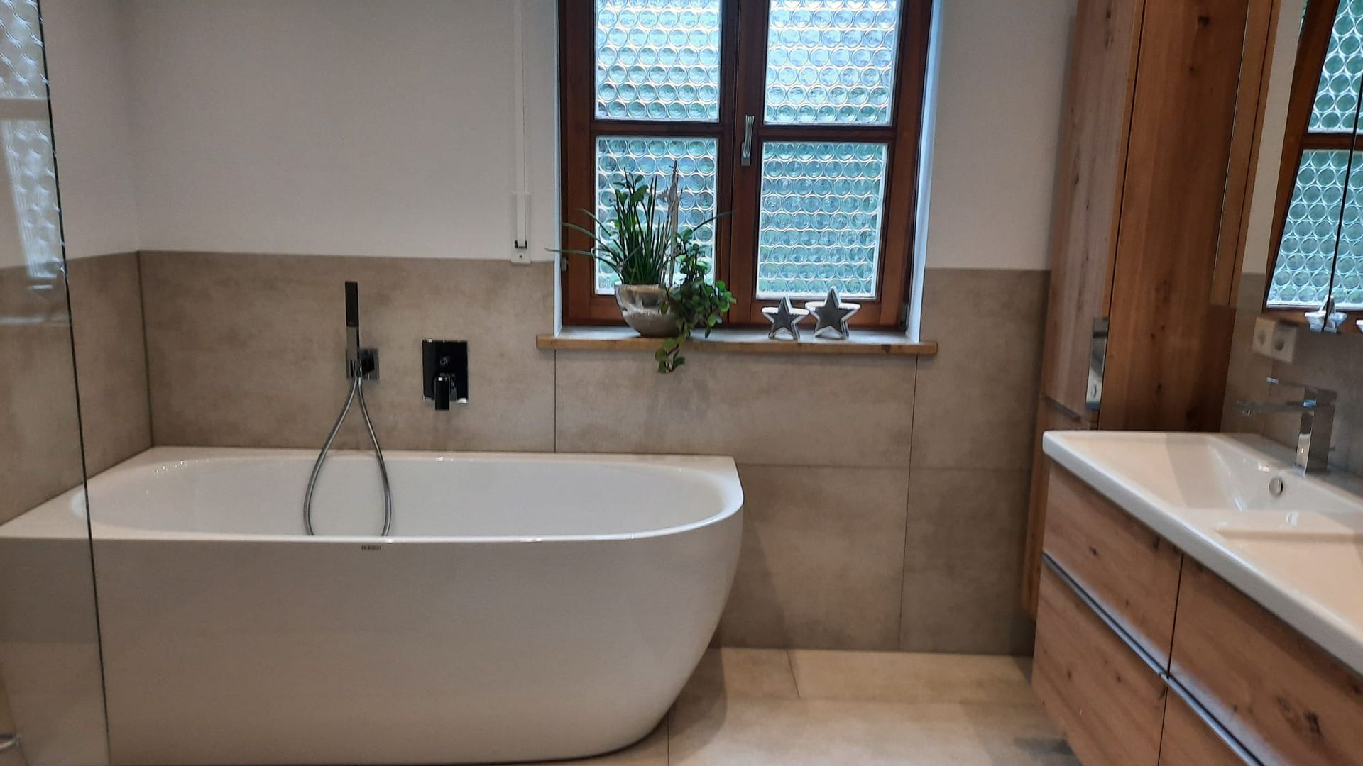 Helles Badezimmer mit Dusche, Waschbecken und eleganten Fliesen.