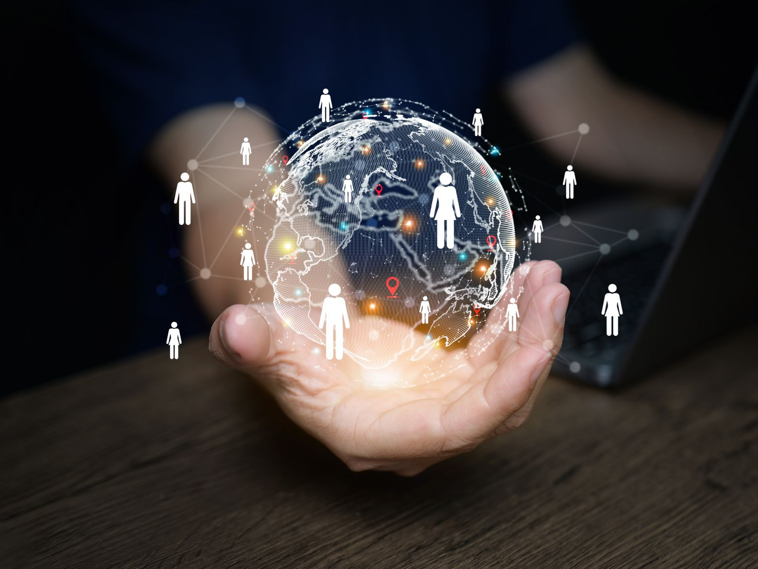 Main tenant un globe lumineux orné d'icônes humaines interconnectées ; symbolisant la mise en réseau et la technologie à l'échelle mondiale.