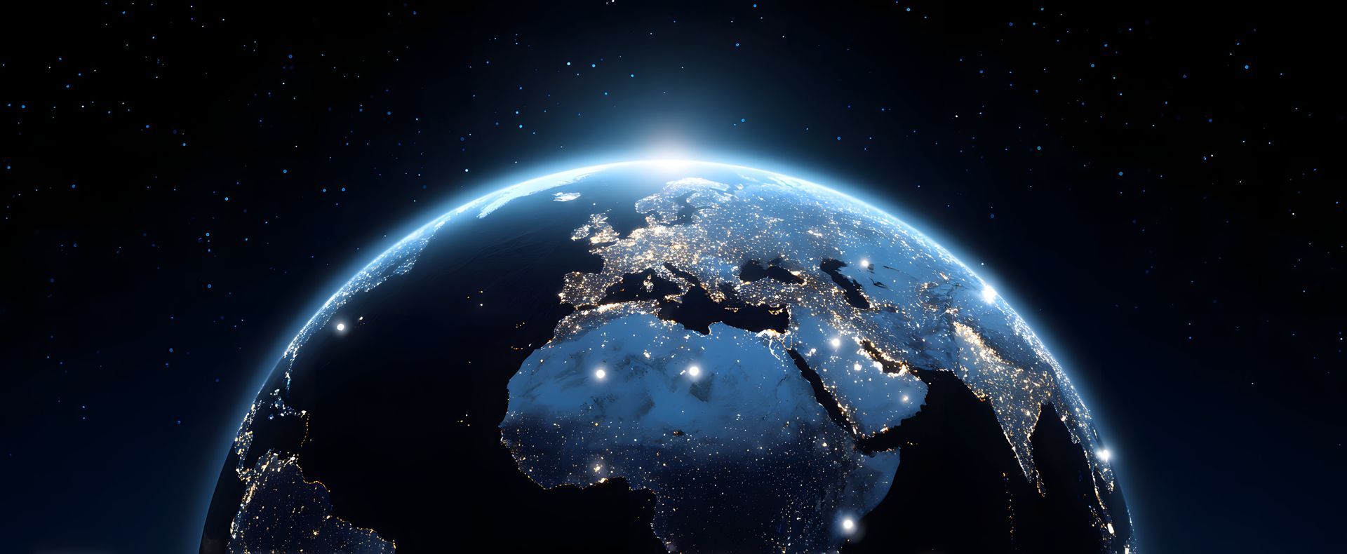 La Terre la nuit, vue de l'espace, montrant les lumières des villes sur terre et une lueur vive à l'horizon.