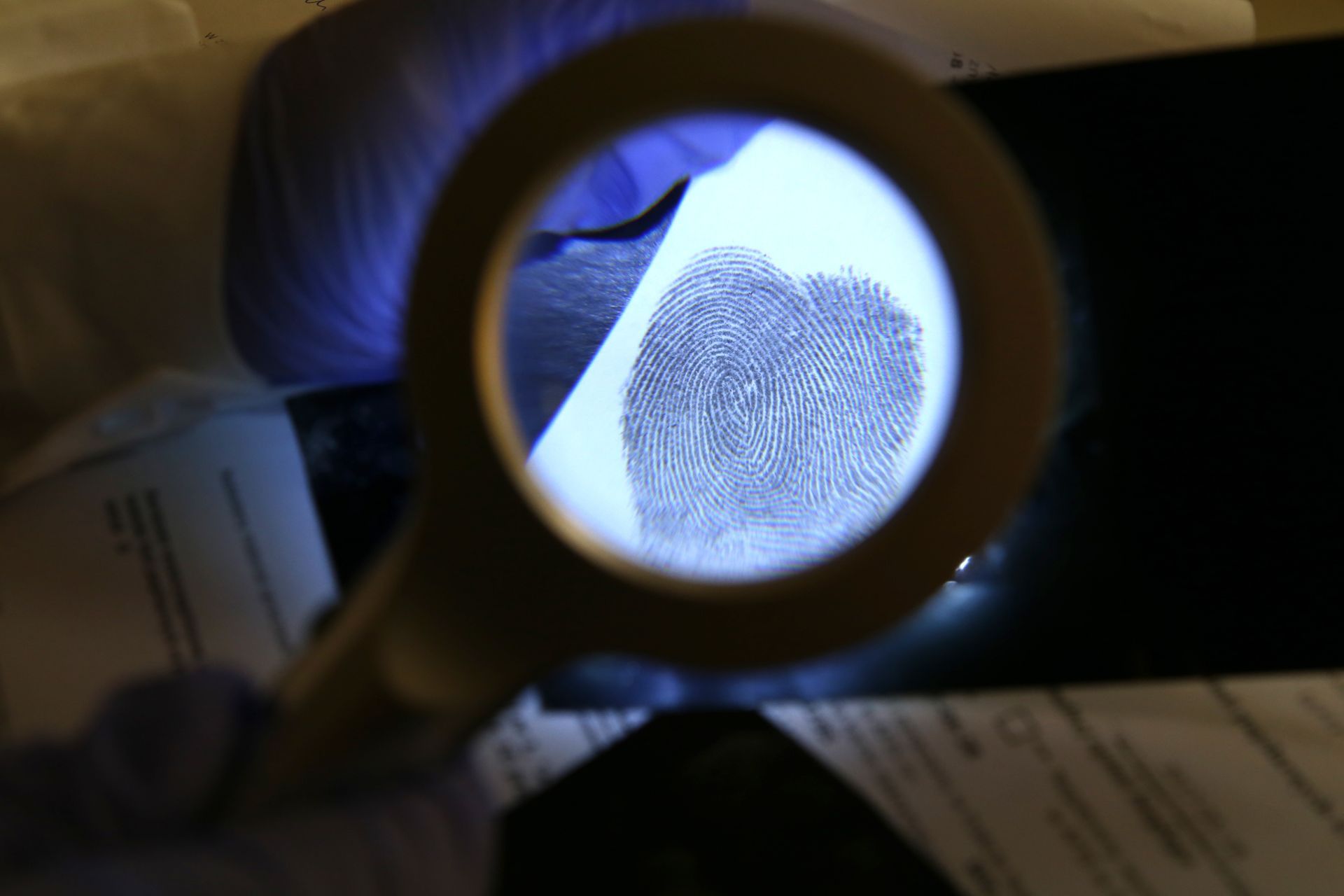 Une empreinte digitale agrandie et observée à la loupe ; enquête sur les lieux du crime.