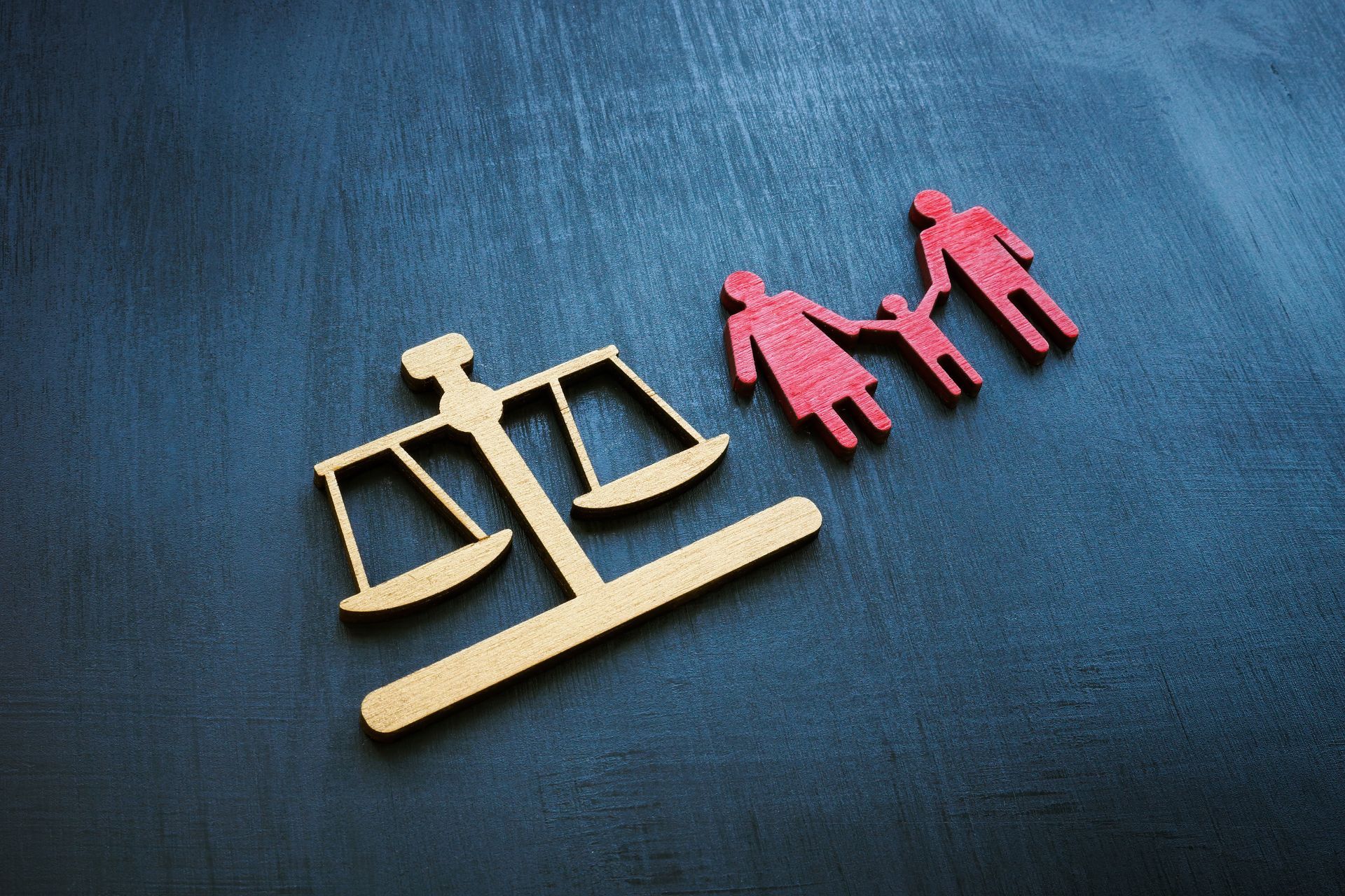 Balance de la justice à côté d'une silhouette familiale en bois ; concept de droit familial.