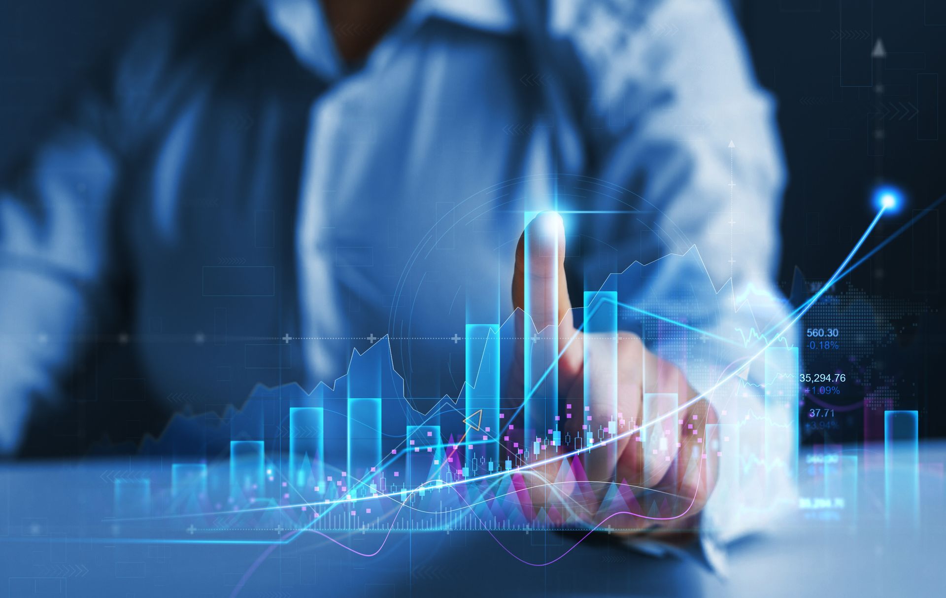 Une personne désigne du doigt un graphique de croissance financière ascendante, représenté en lumière bleue.