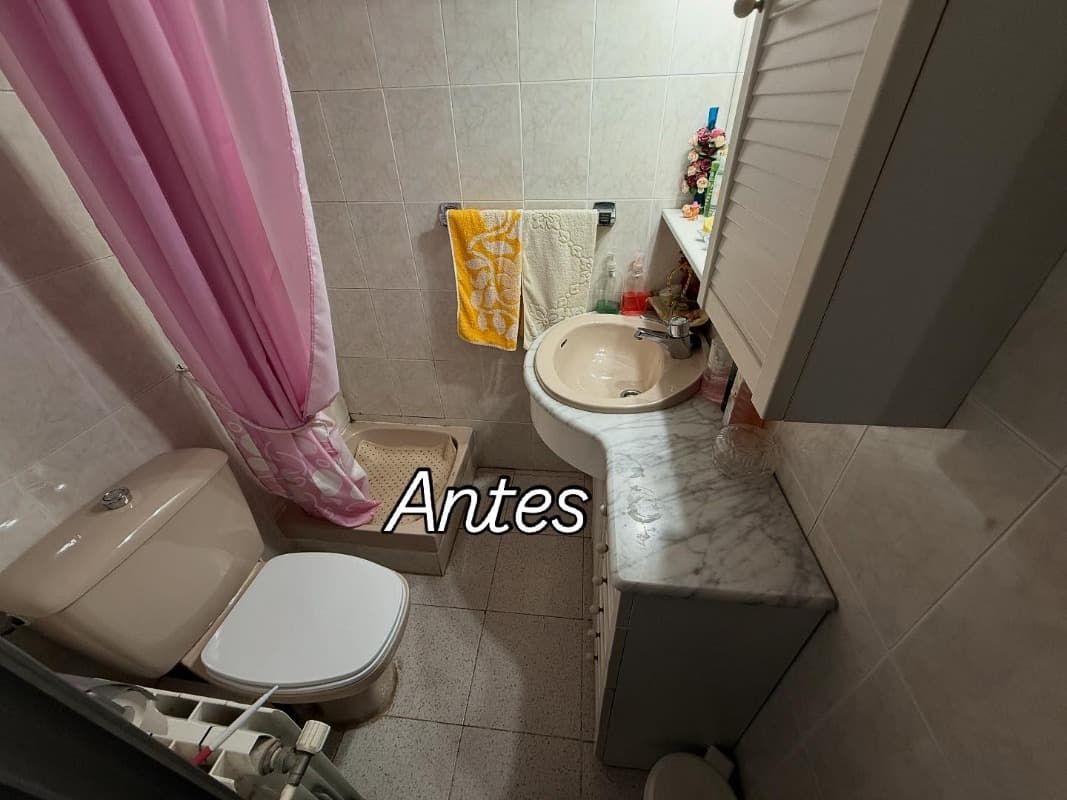 Baño pequeño con inodoro, lavabo, paredes alicatadas, cortina rosa y texto superpuesto 