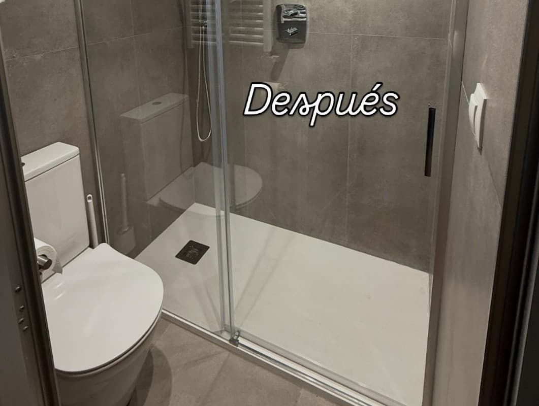 Baño pequeño con cabina de ducha de cristal e inodoro, con la inscripción 