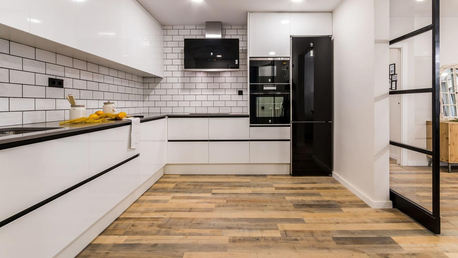 Una cocina con gabinetes blancos y piso de madera.