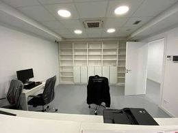 Una habitación con un escritorio, sillas, una computadora y una impresora.