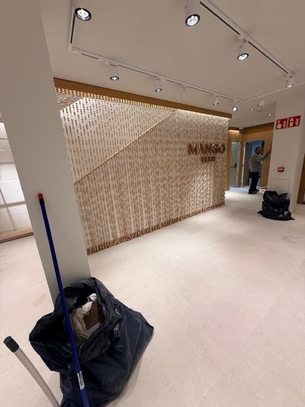 Vestíbulo luminoso con pared estampada, suelo blanco, luces de techo y artículos de limpieza en primer plano.