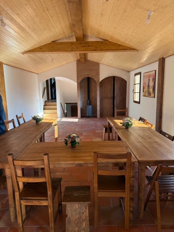 Comedor con paneles de madera, mesa larga, sillas de madera y chimenea arqueada en la pared del fondo.