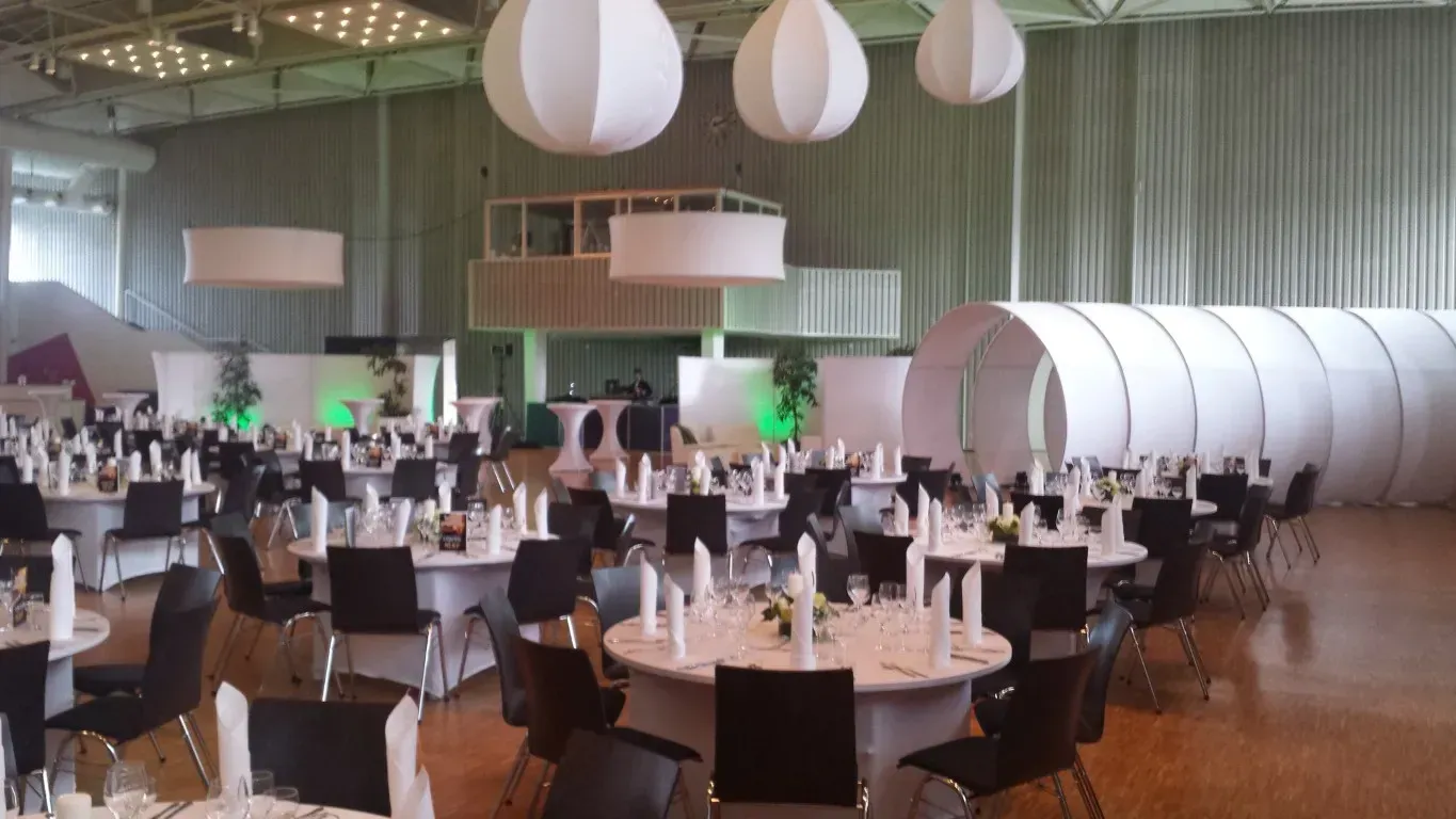 Ein großer Saal mit vielen Tischen und Stühlen für eine Hochzeitsgesellschaft