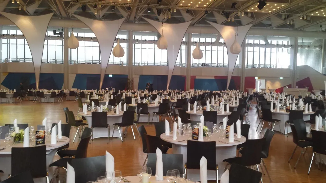 Ein großer Raum mit vielen Tischen und Stühlen für ein Firmenevent