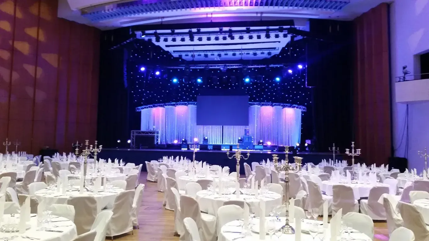 Ein großer Saal mit Tischen und Stühlen und einer Bühne