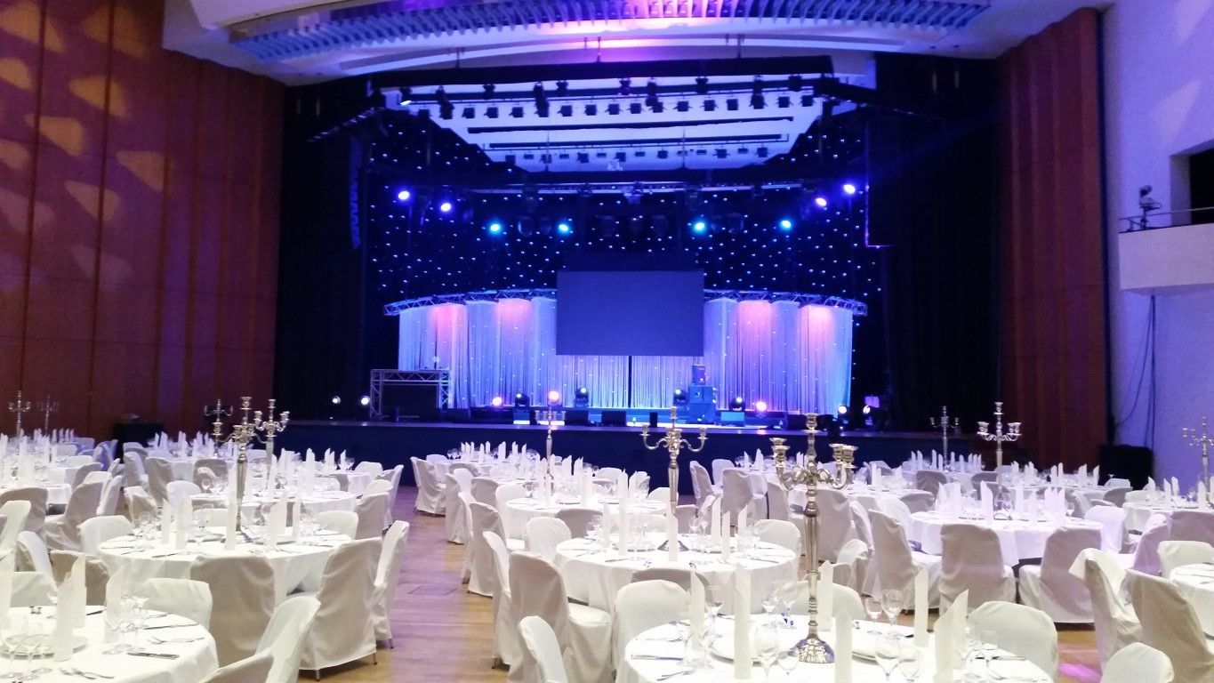 Eventlocation für eine Hochzeit mit Bühne und Tischdekorationen