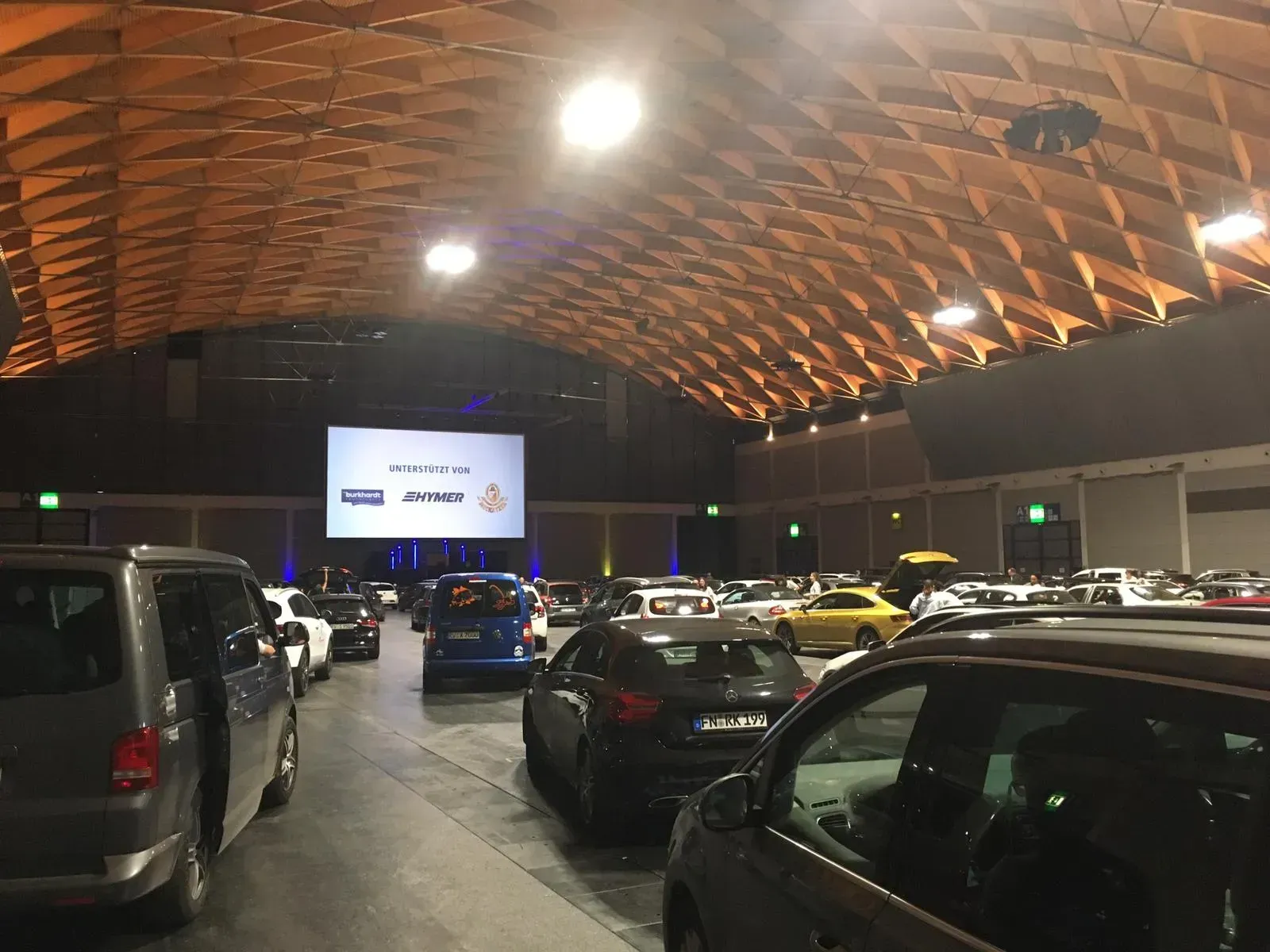 Eine Reihe von Autos, die in einer großen Messehalle stehen, zu Ausstellungszwecken