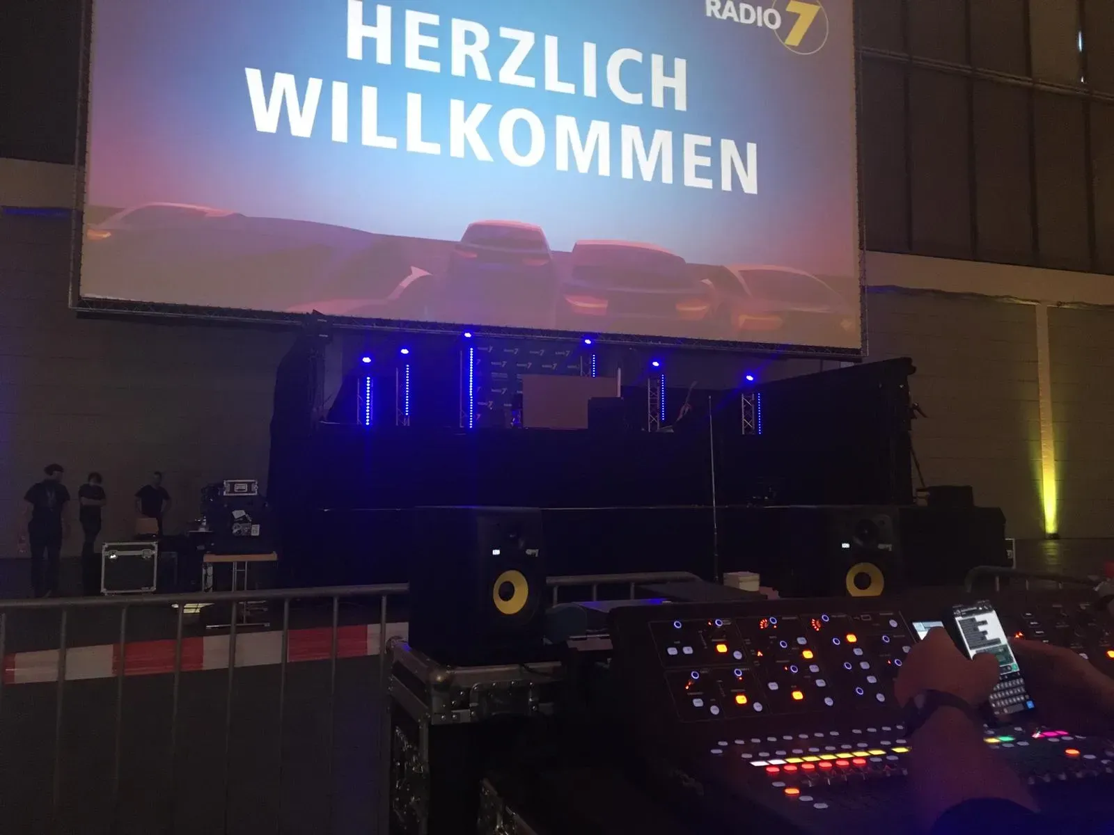 Ein DJ steht vor einem großen Bildschirm mit der Aufschrift herzlich willkommen