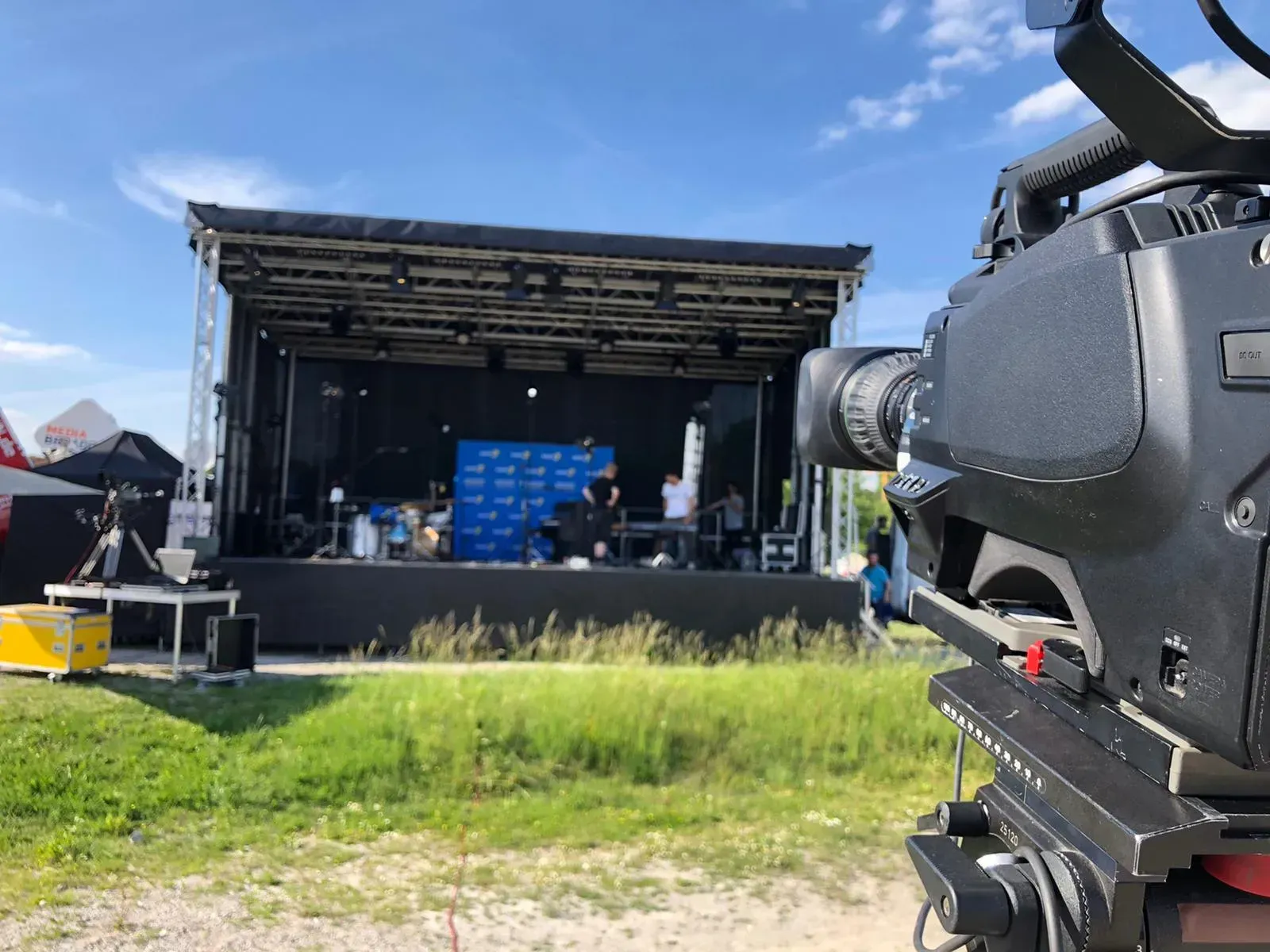Ein Kamerateam steht vor einer Bühne mit Menschen darauf