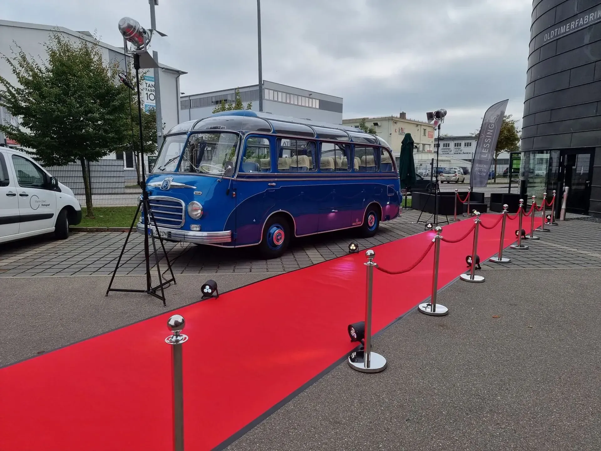 Eingangsbereich mit rotem Teppich und Oldtimerbus