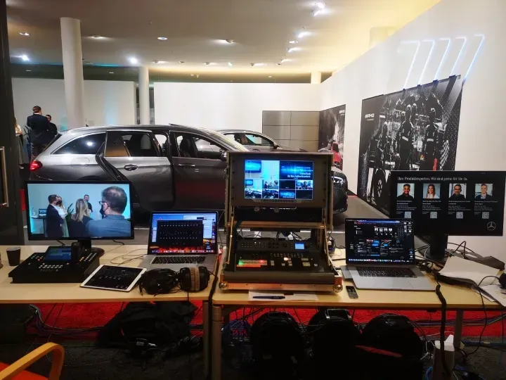 Ein Auto steht hinter einem Tisch mit Laptops und Bildschirmen