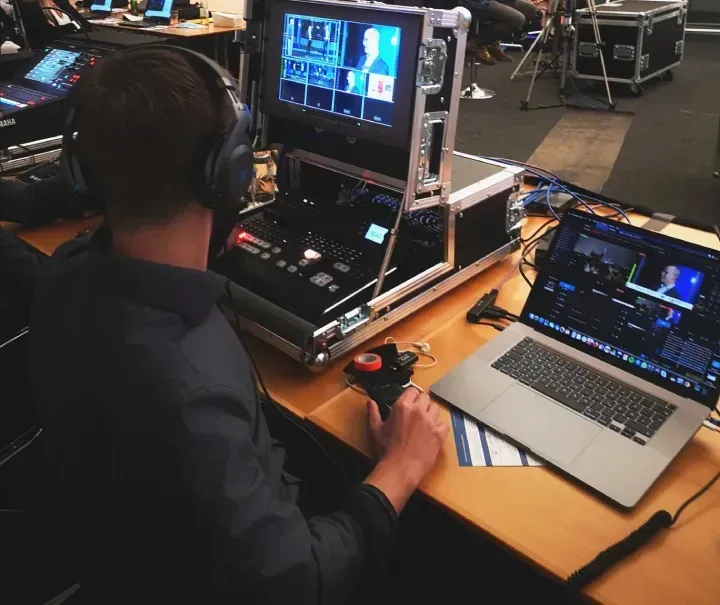 Ein Mann sitzt an einem Tisch mit Kopfhörern und einem Laptop