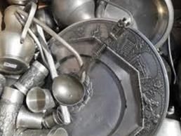 Auf einem Tisch liegen übereinander gestapelte Aluminiumutensilien und Teller.