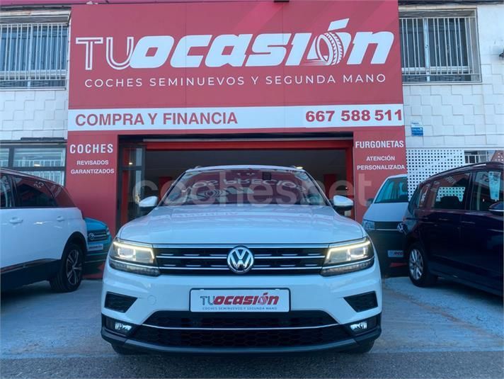 Un Volkswagen blanco está estacionado frente a un concesionario de automóviles.