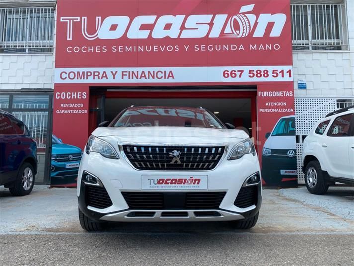 Un coche blanco está aparcado delante de un concesionario de coches.