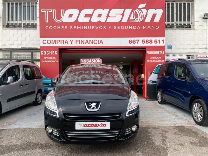Un coche negro está aparcado frente a una tienda llamada tu ocasion