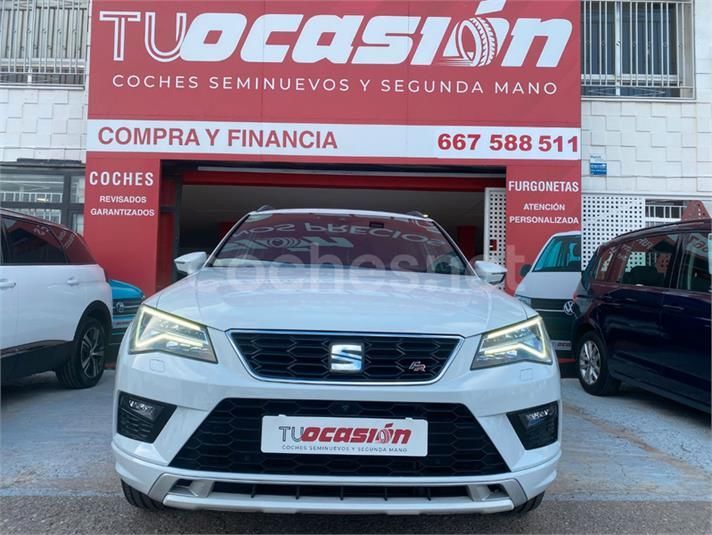 Un coche blanco está aparcado delante de un cartel de 