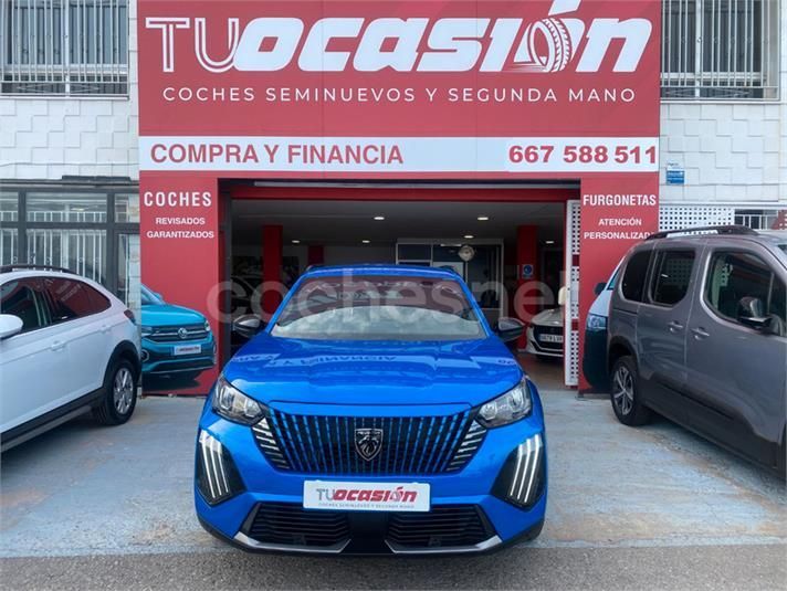 Un coche azul está aparcado delante de un concesionario de coches.