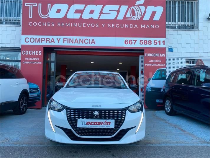 Un coche blanco está aparcado delante de un cartel de Tucasion.