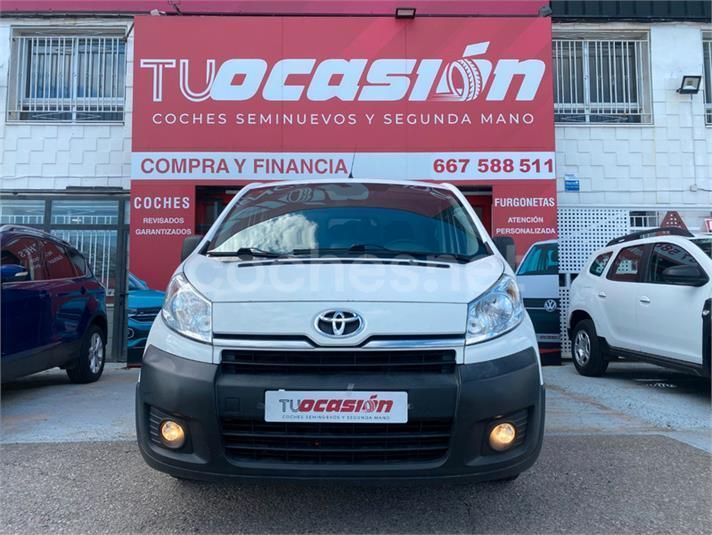 Una camioneta Toyota blanca está estacionada frente a una tienda de artículos de ocasión.
