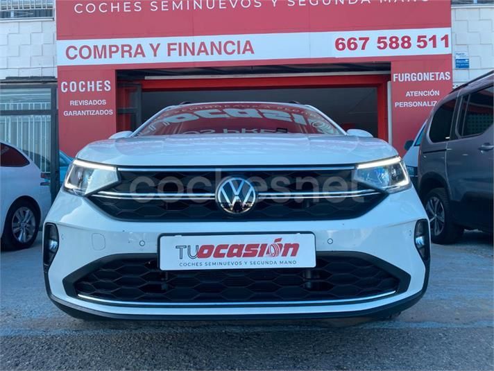 Un coche blanco está aparcado delante de un cartel rojo que dice compra y financia