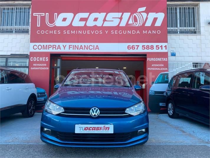 Un coche azul está aparcado delante de una tienda de artículos de ocasión.