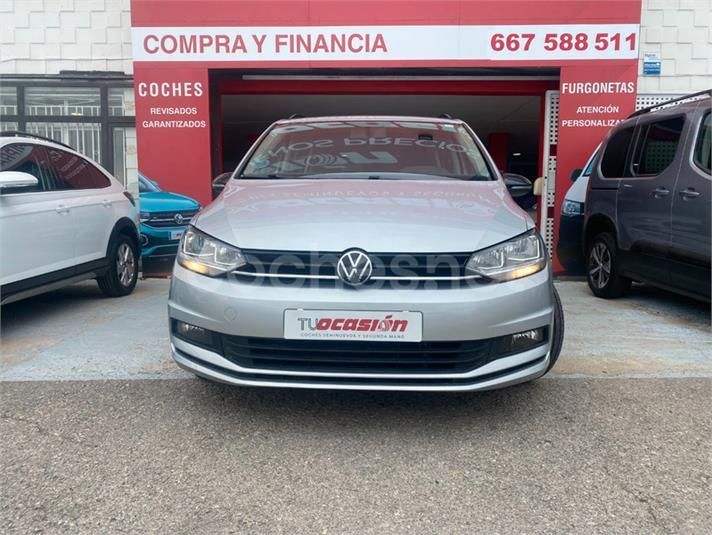 Un Volkswagen Golf plateado está aparcado delante de un concesionario de coches.