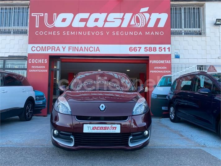Un coche rojo está aparcado frente a un concesionario de coches Tucasion.
