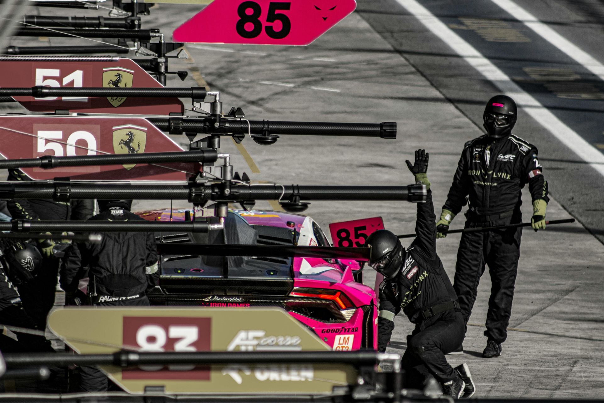 Un hombre está trabajando en un coche de carreras en un pit lane.