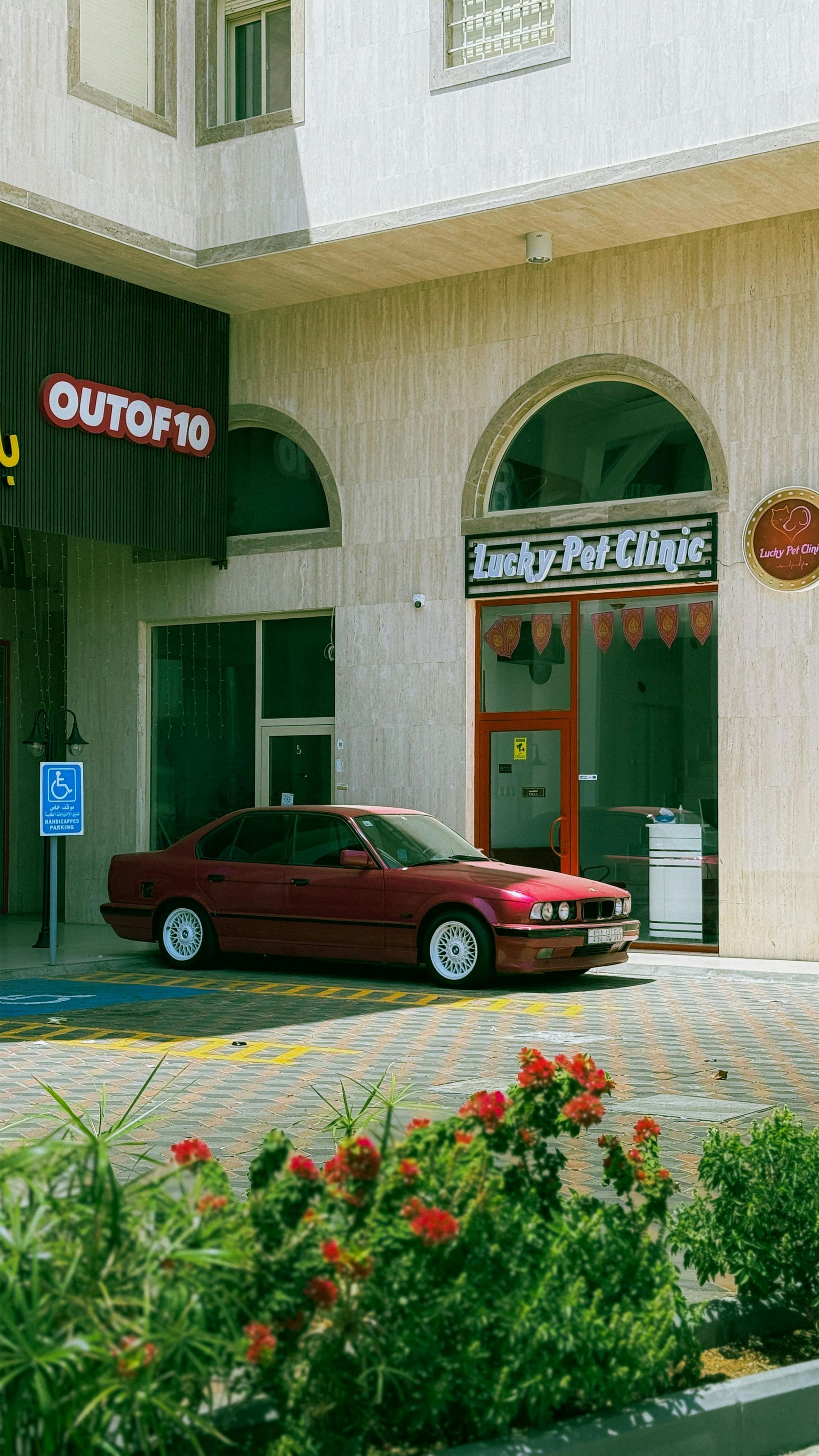 Un coche rojo está aparcado delante de un edificio.