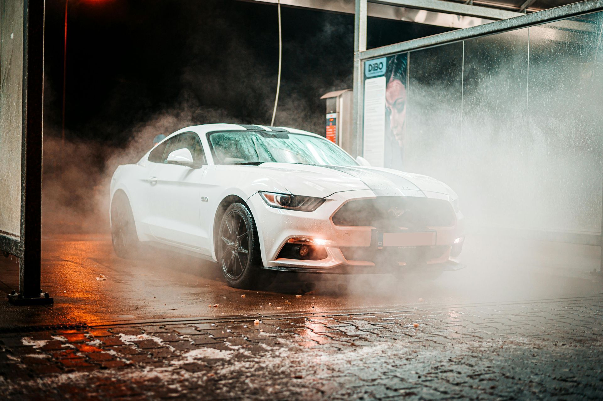 Un Ford Mustang blanco está siendo lavado en un lavadero de autos.