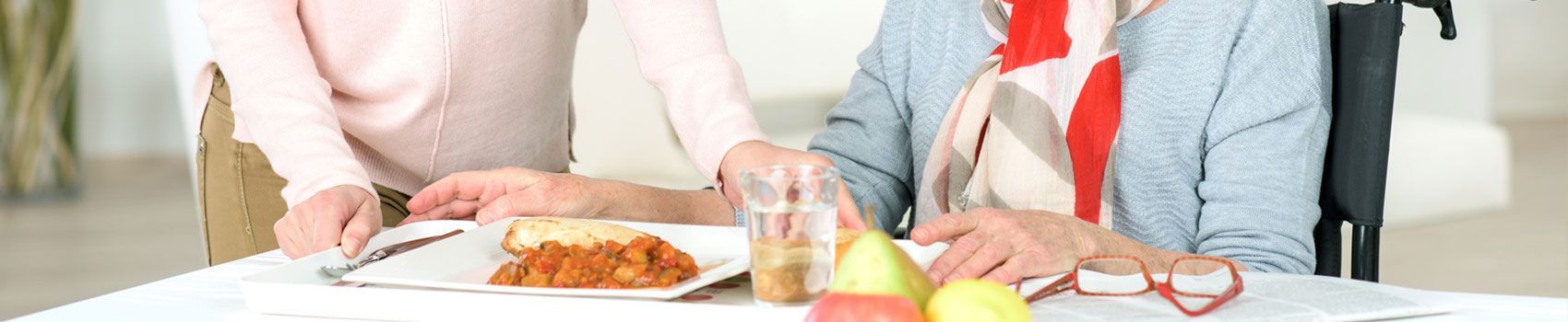 Ein älteres Paar sitzt mit Tellern voller Essen an einem Tisch.