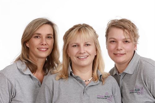 Drei Frauen in grauen Poloshirts posieren für ein Foto.