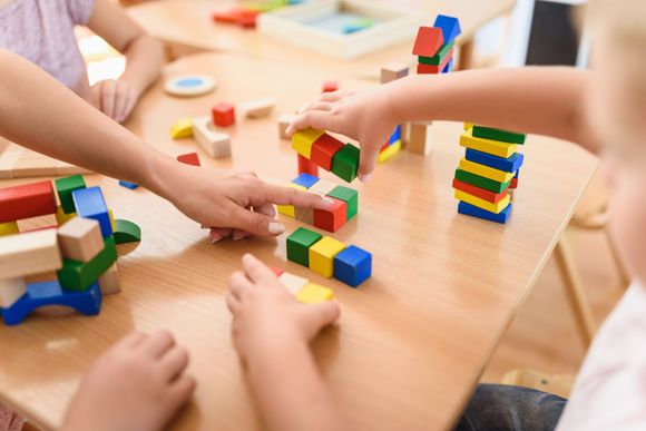 Eine Gruppe Kinder spielt an einem Tisch mit Holzklötzen.